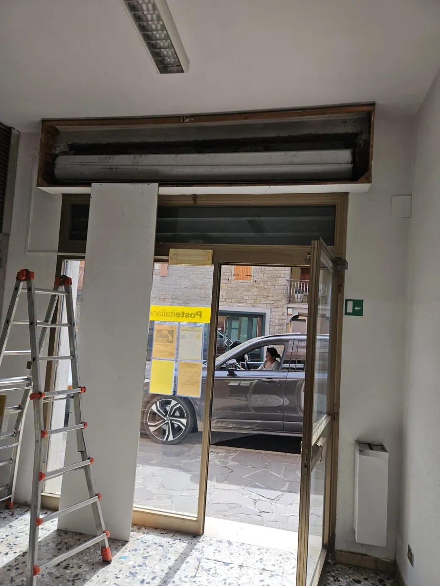 Riparazione della serranda di un negozio a Bologna: cassonetto aperto e rullo in lavorazione